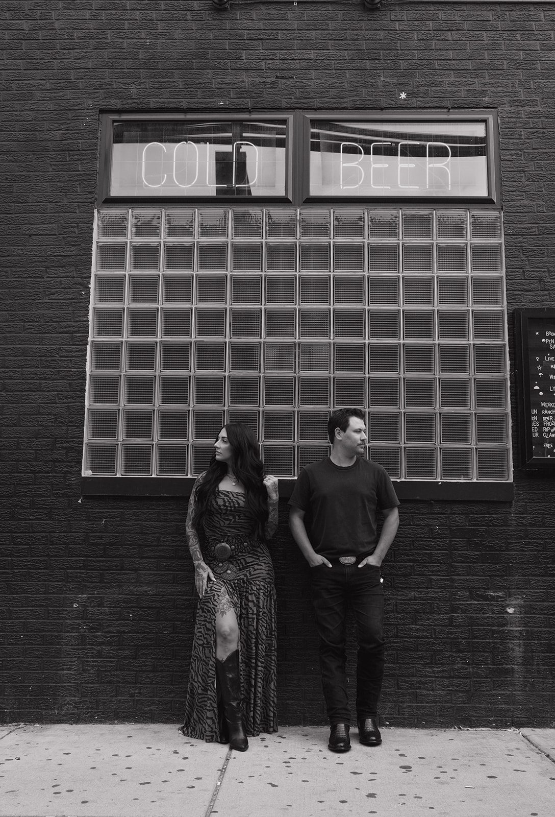 A black and white photo of a couple outside of a bar for a cuples photoshoot