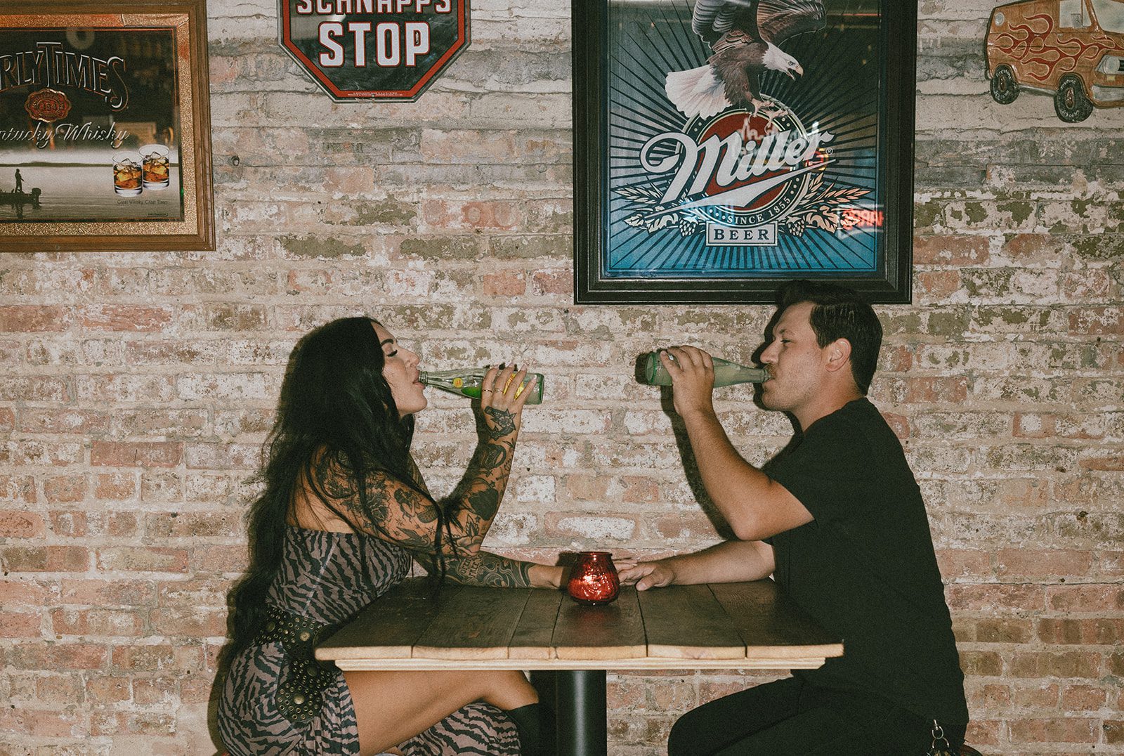 A couple drinking beer together inside of a bar for their couples photoshoot