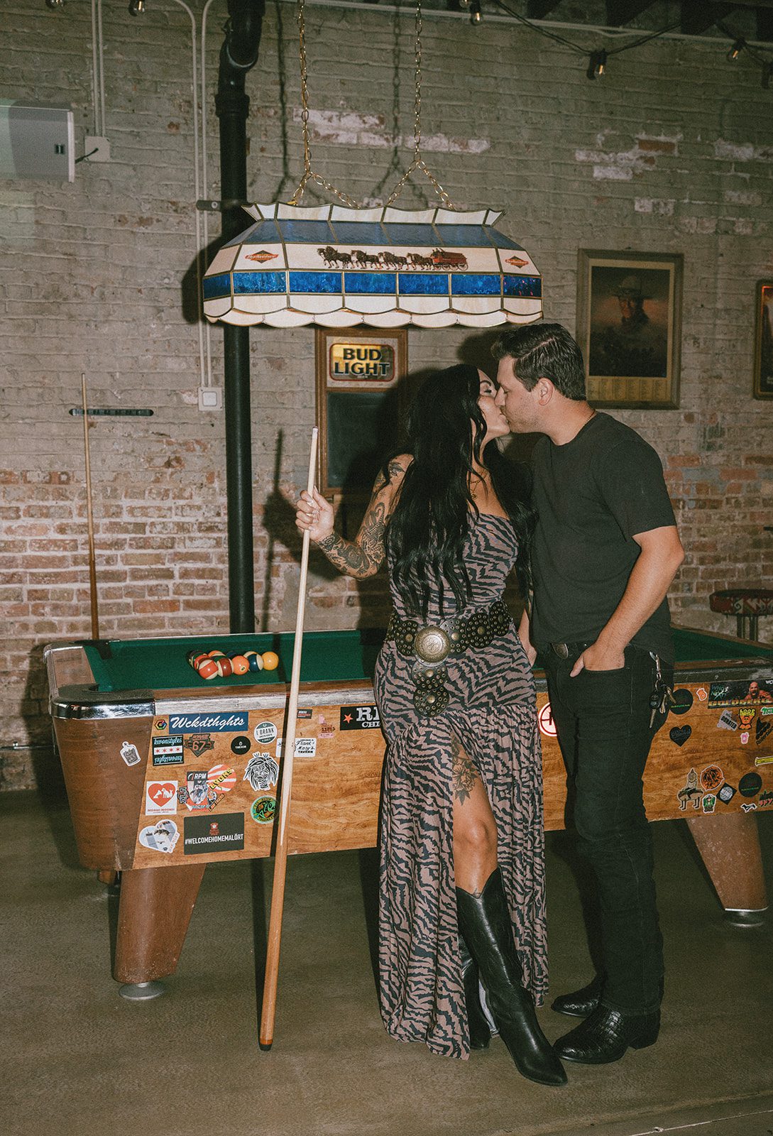 A couple kissing beside a pool table
