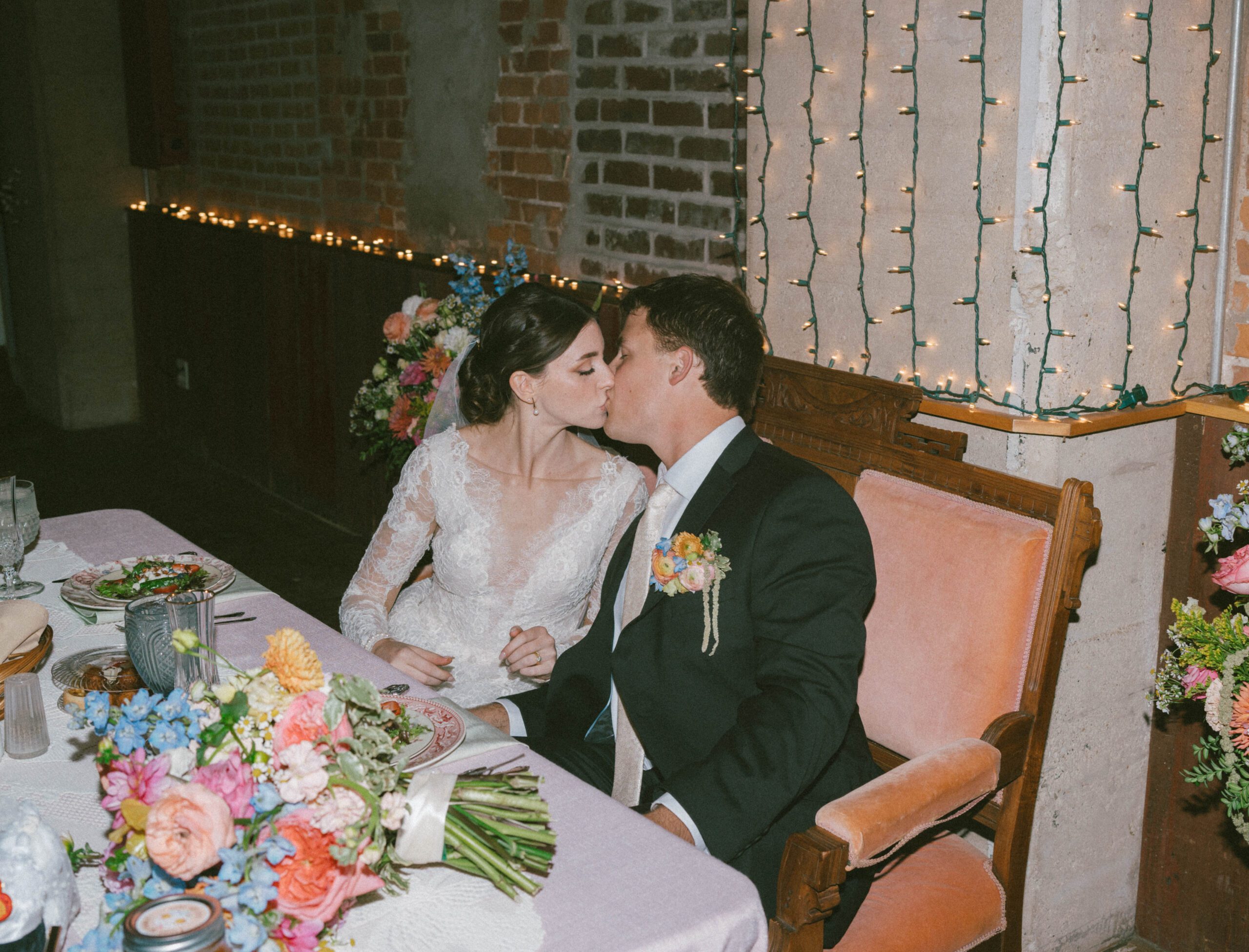 A couple kissing at their sweetheart table at Blumen Gardens