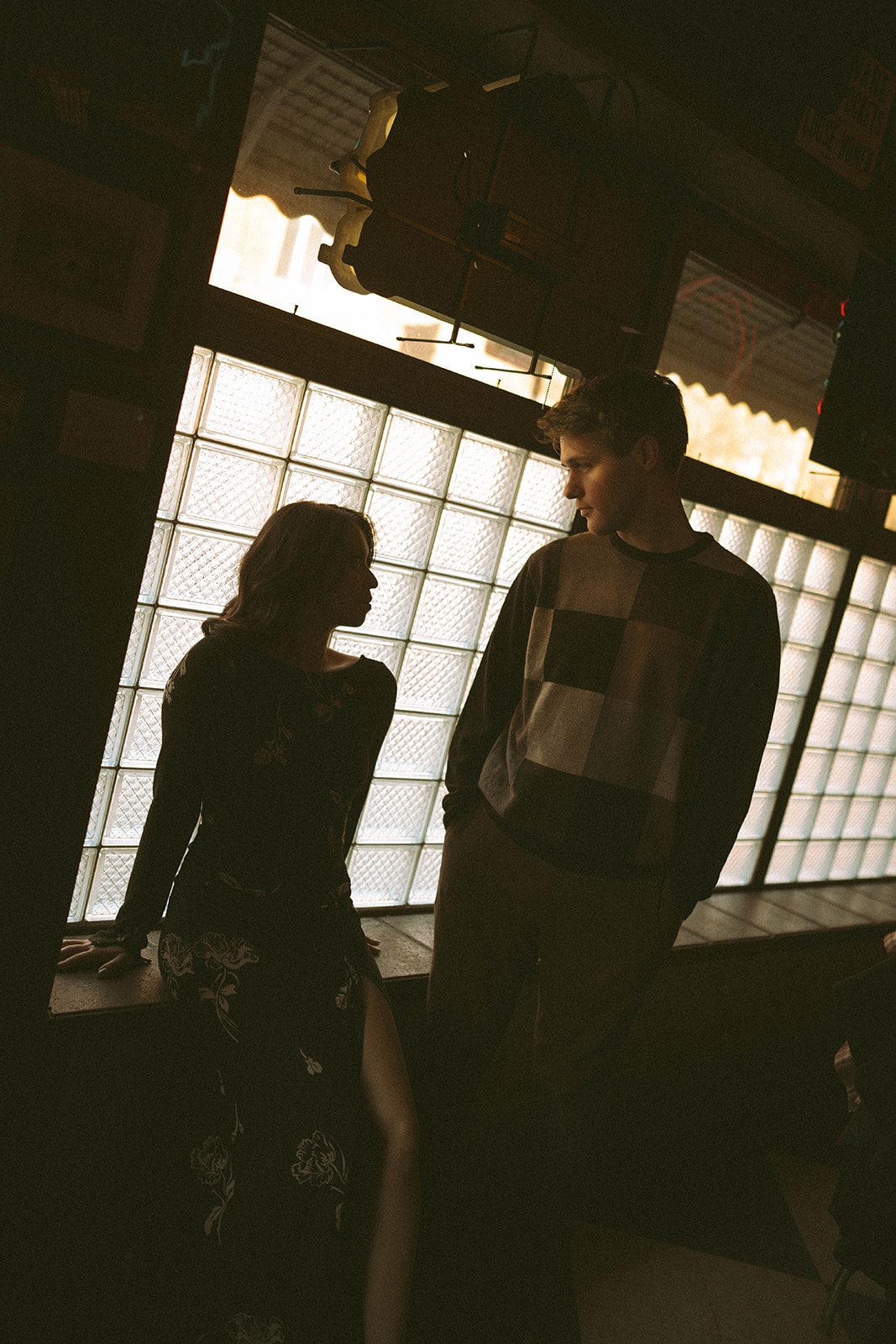 A couple sitting in front of a window in a bar for engagement photoshoot ideas
