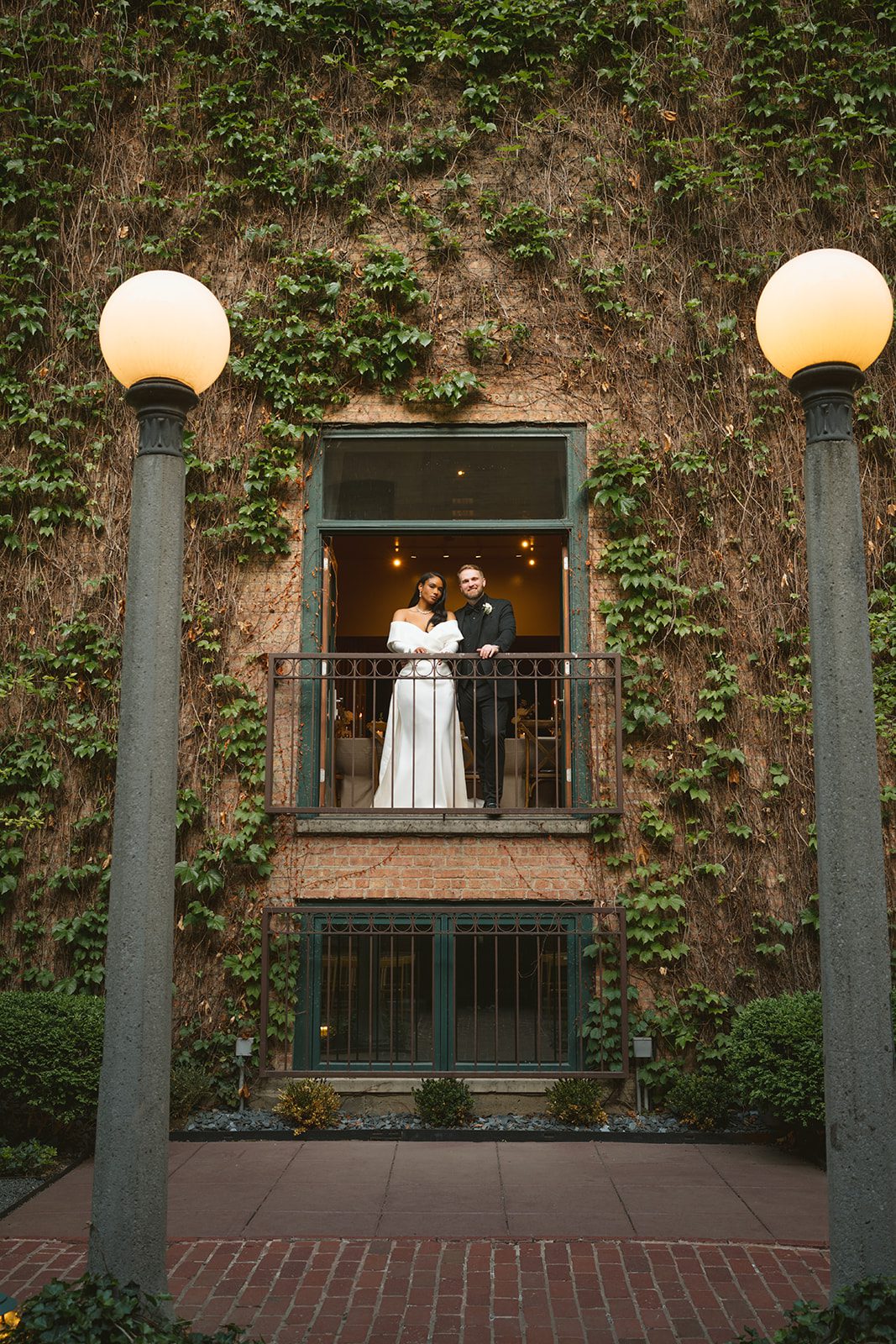 A bride and groom posing on the balcony at the ivy room for wedding photos