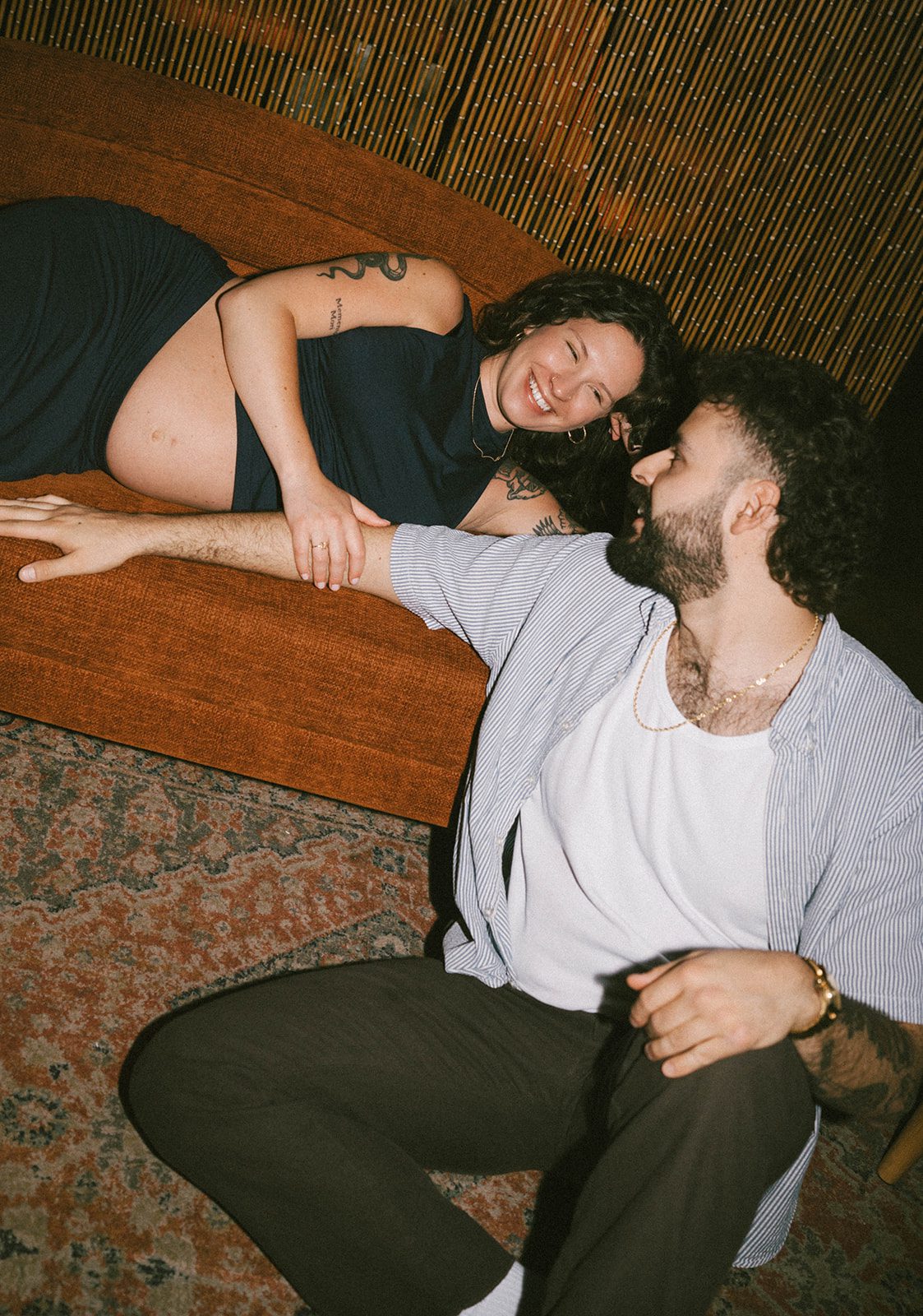 A couple laughing during their maternity photoshoot