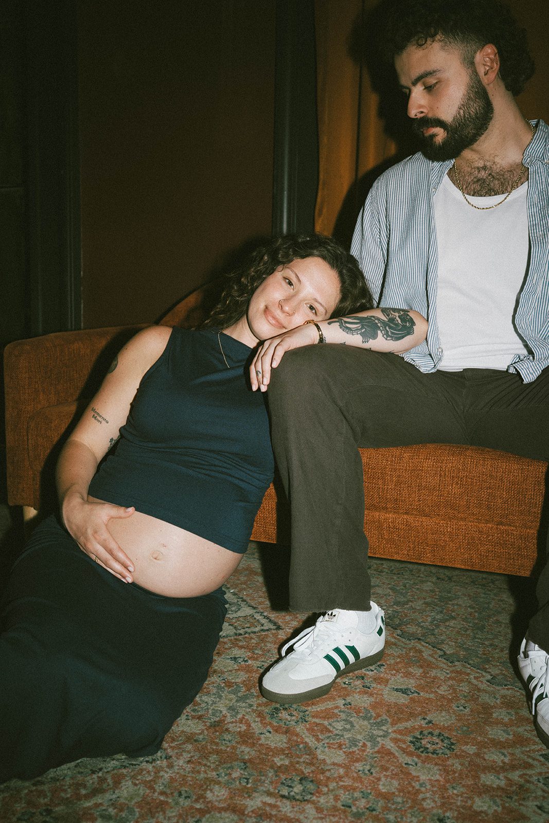 A woman leaning her head against her husband's leg during maternity photos