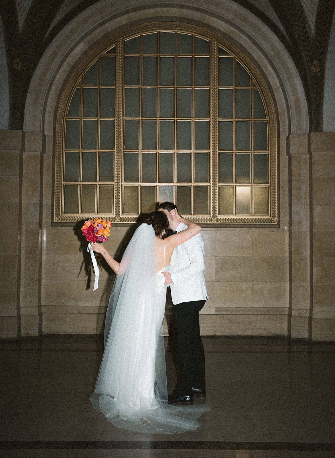 A couple kissing in front of the arched windows at their chicago courthouse wedding