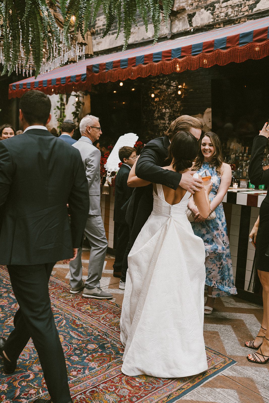 A candid photo of a bride hugging a guest at a wedding reception