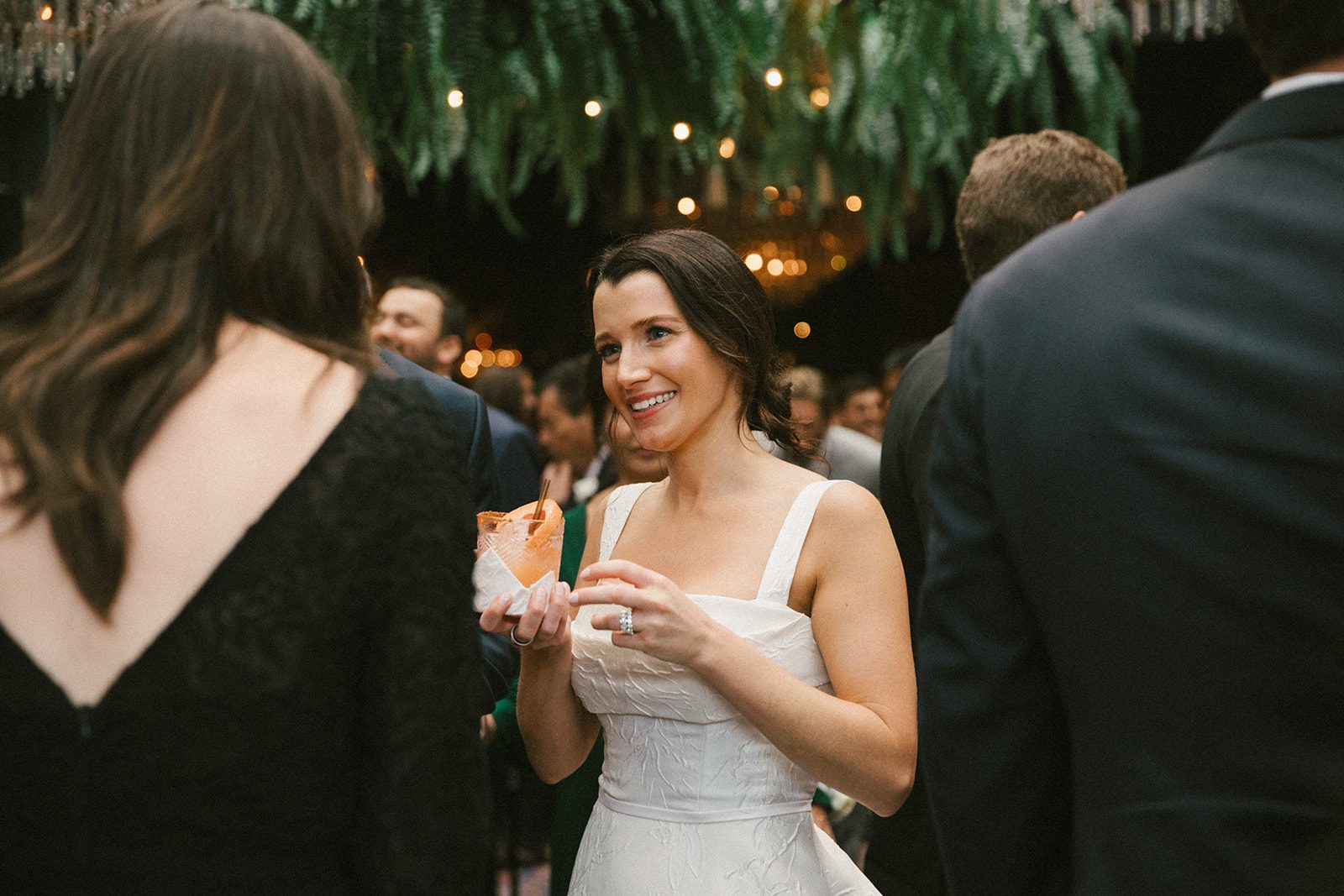 A bride talking to wedding guests at cocktail hour in a candid wedding photo