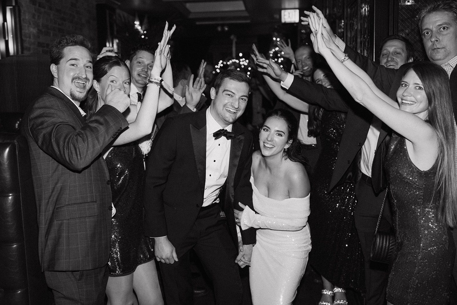 A bride and groom between cheering wedding guests