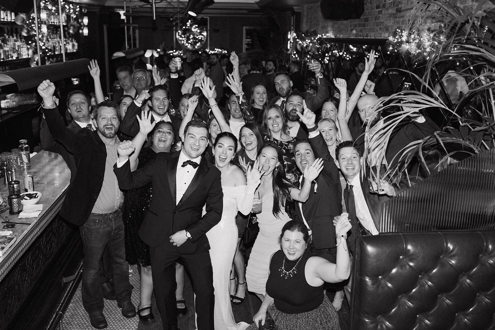 Wedding guests cheering in a black and white photo taken at celeste chicago