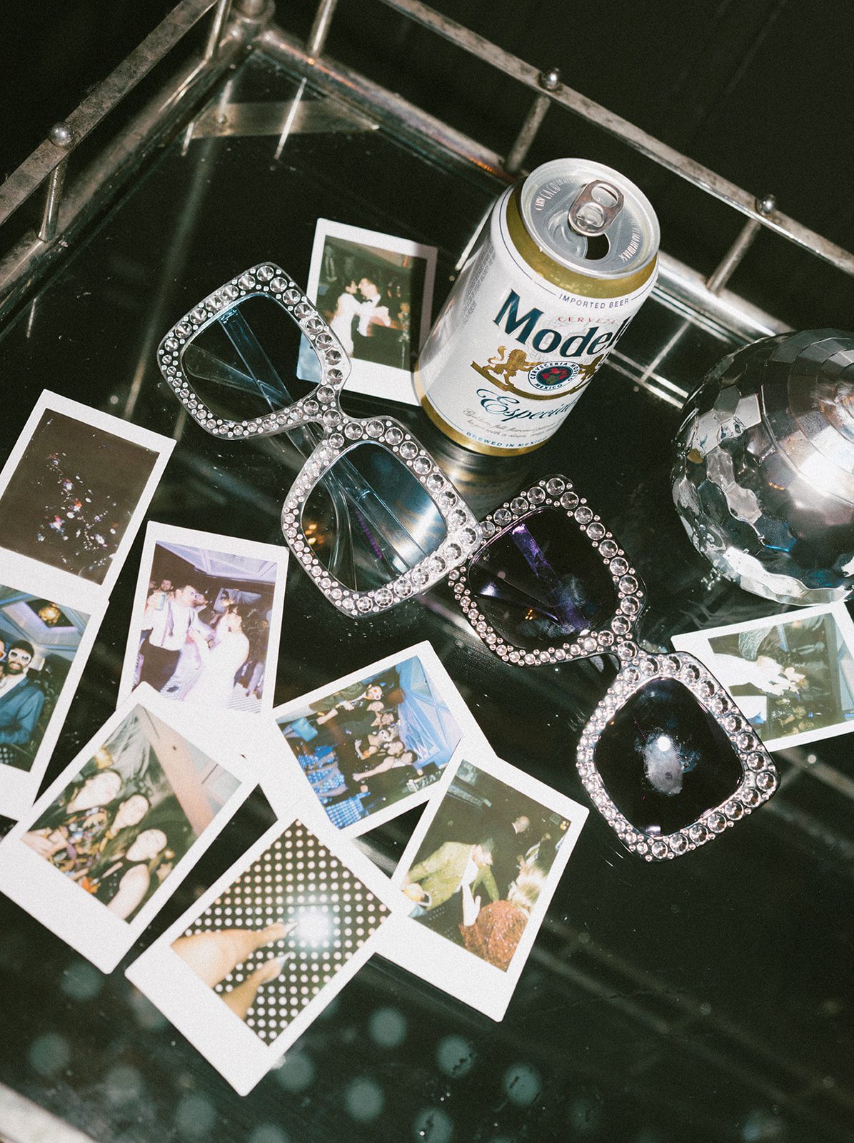 A beer, polaroids, and sparkly glasses at a wedding reception