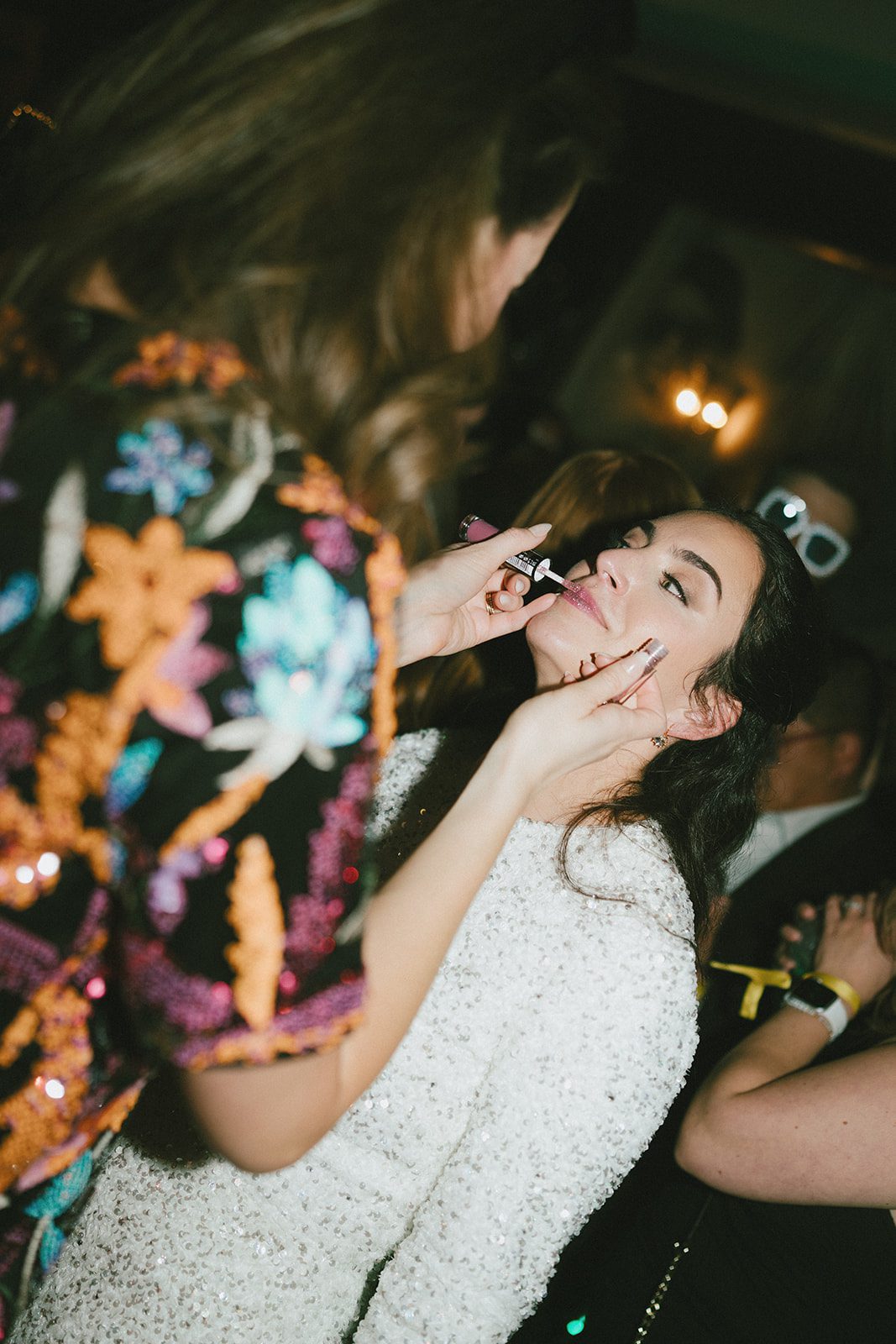 A wedding guest putting lipstick on the bride