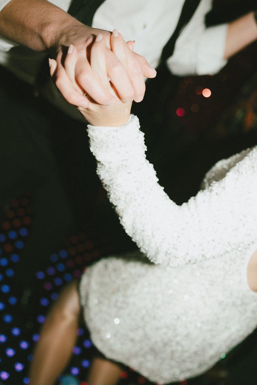 A bride and groom's hands holding while on their wedding dance floor