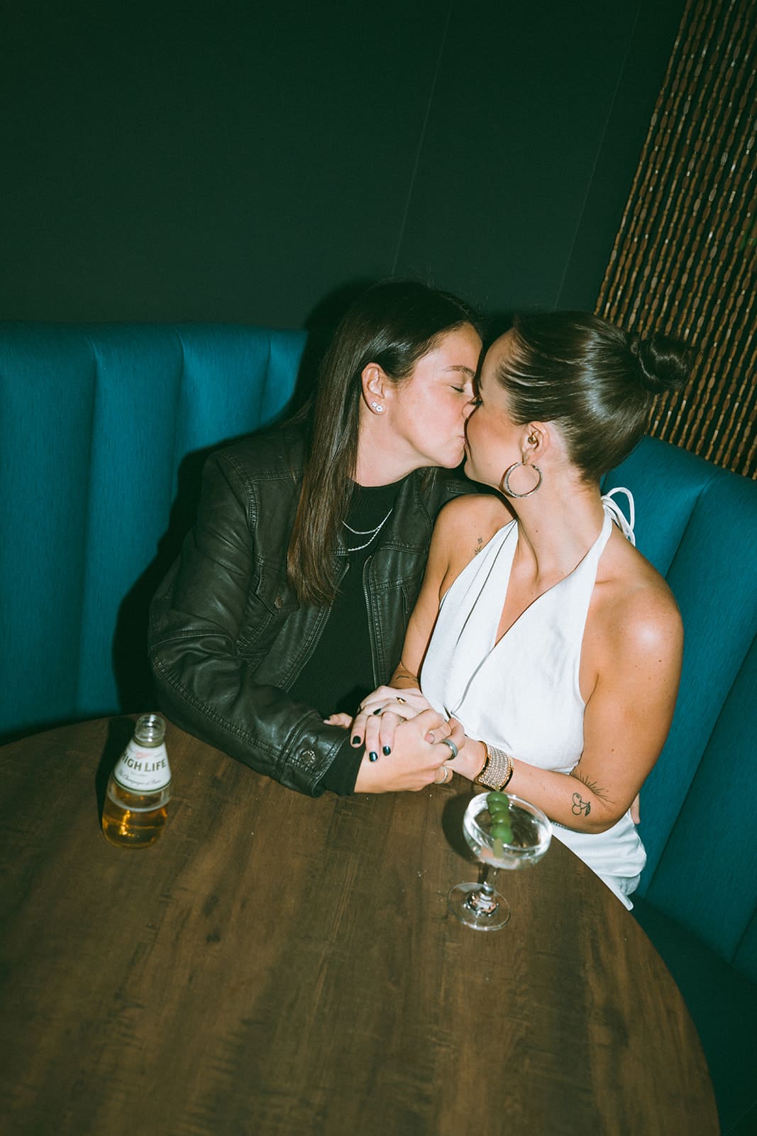 A couple kissing in a booth at a bar for engagement photos