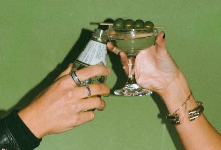 A couple clinking their drinks during a bar engagement photoshoot