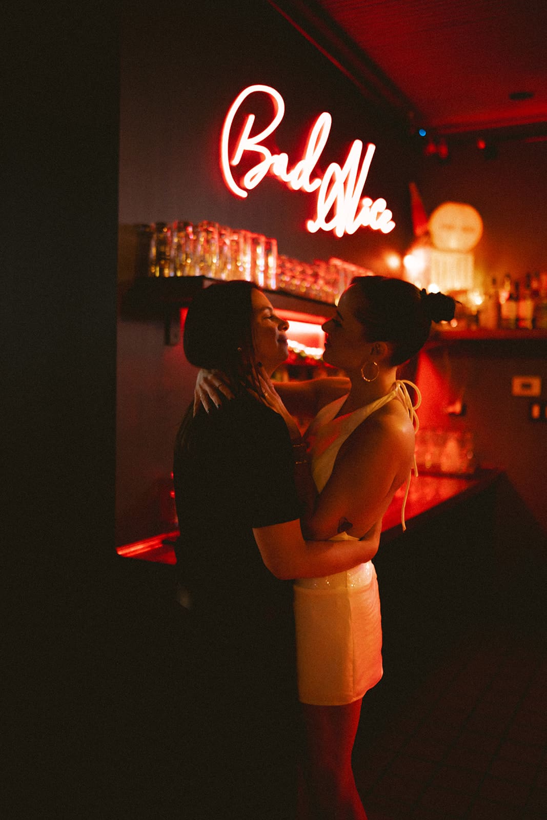 A couple posing for engagement photoshoot ideas in front of a neon sign