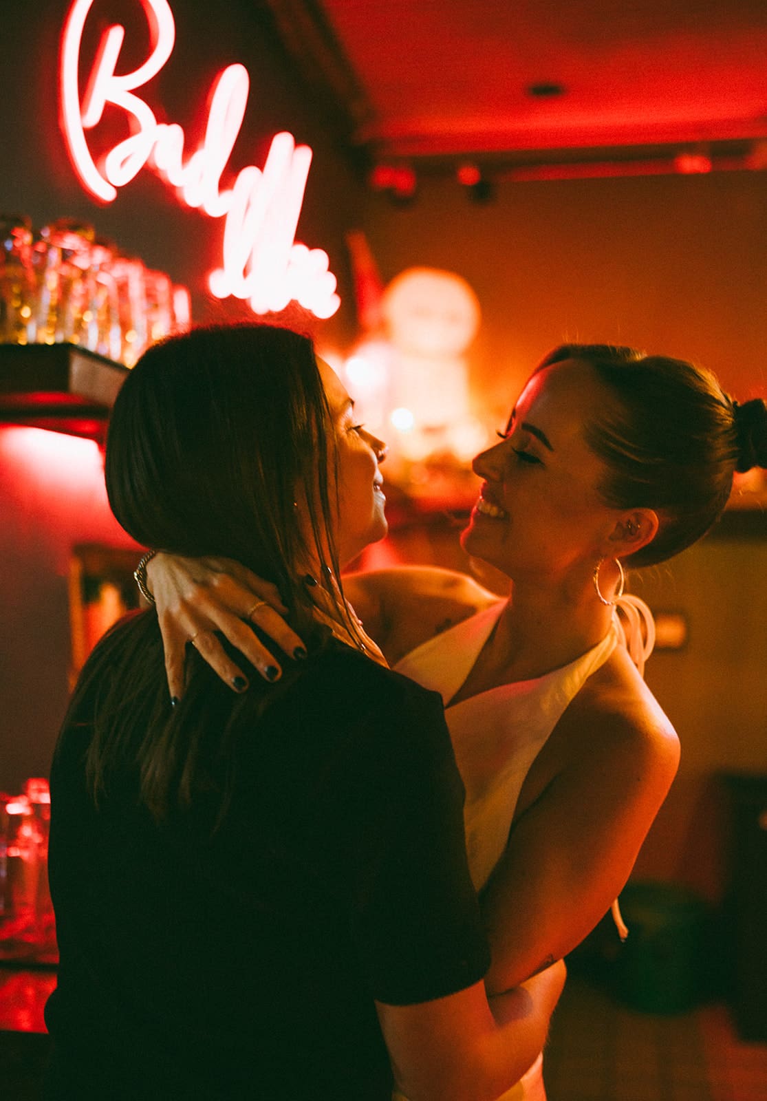 A couple posing for engagement photoshoot ideas in front of a neon sign