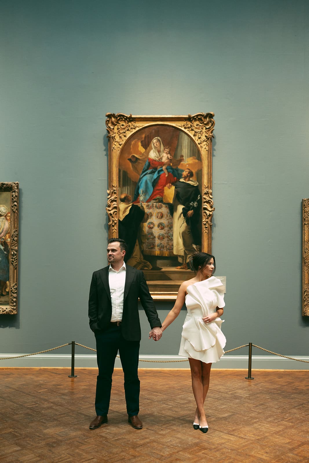 A couple posing for engagement photos in an art museum