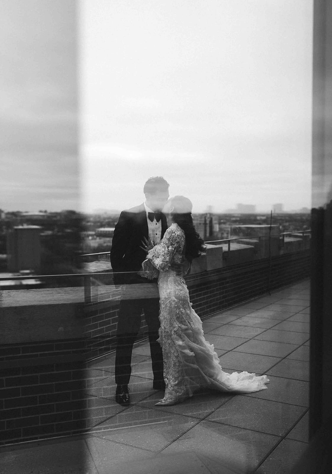 A bride and groom kissing, taken by a Chicago wedding photographer through a window