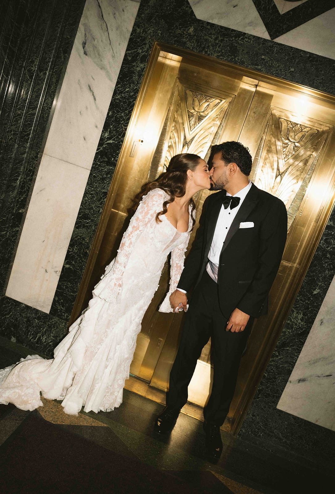 A bride and groom taking pictures in front of an elevator
