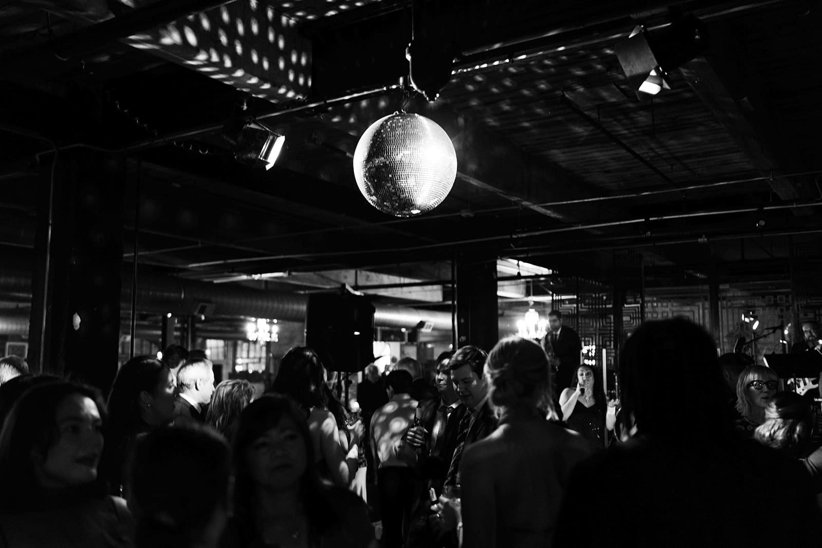 Wedding guests dancing underneath a disco ball at a wedding reception