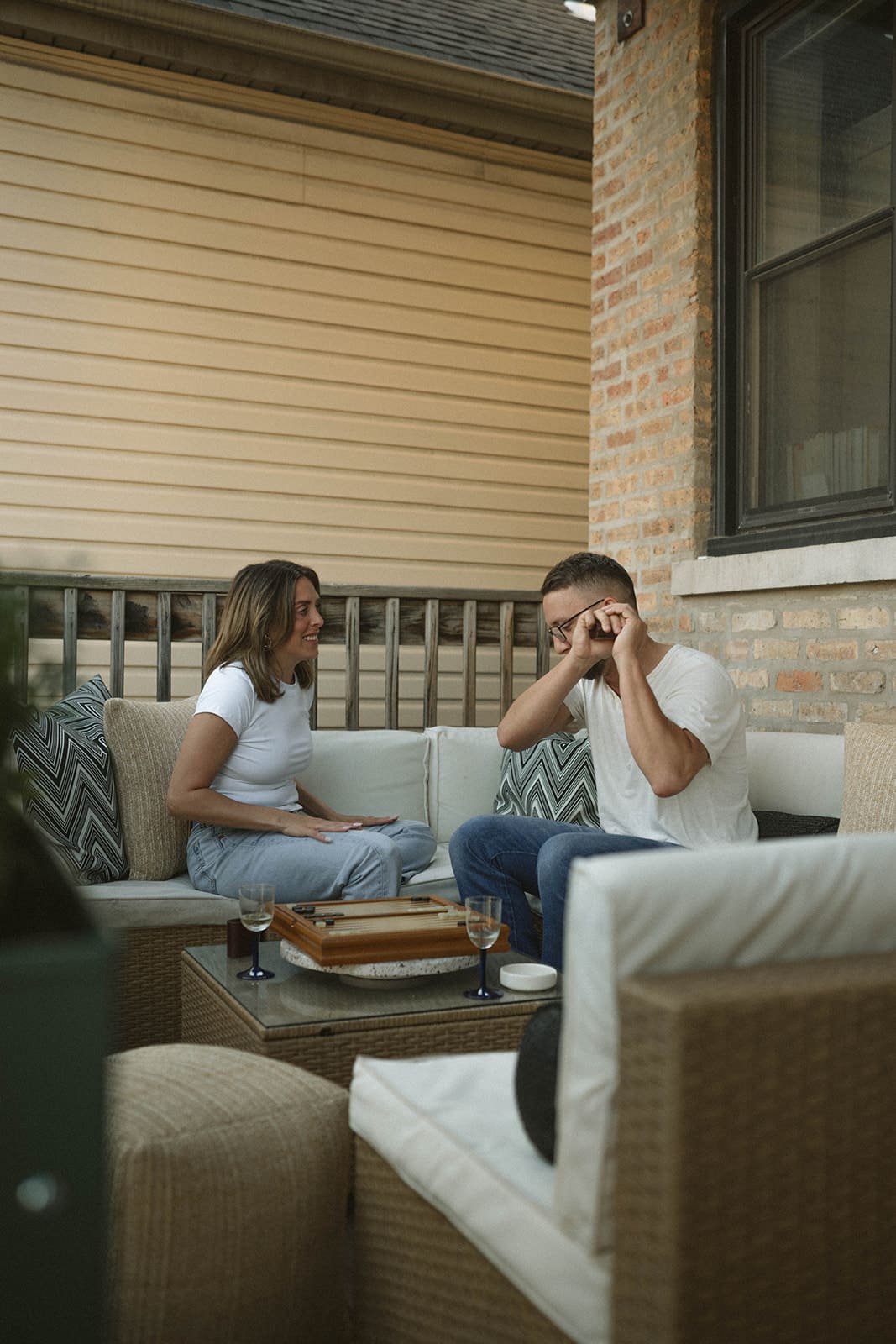 A couple playing a dice game on their back patio for cool engagement photo ideas