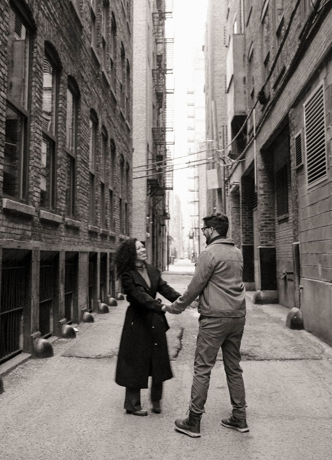 A couple spinning between buildings for their engagement photoshoot