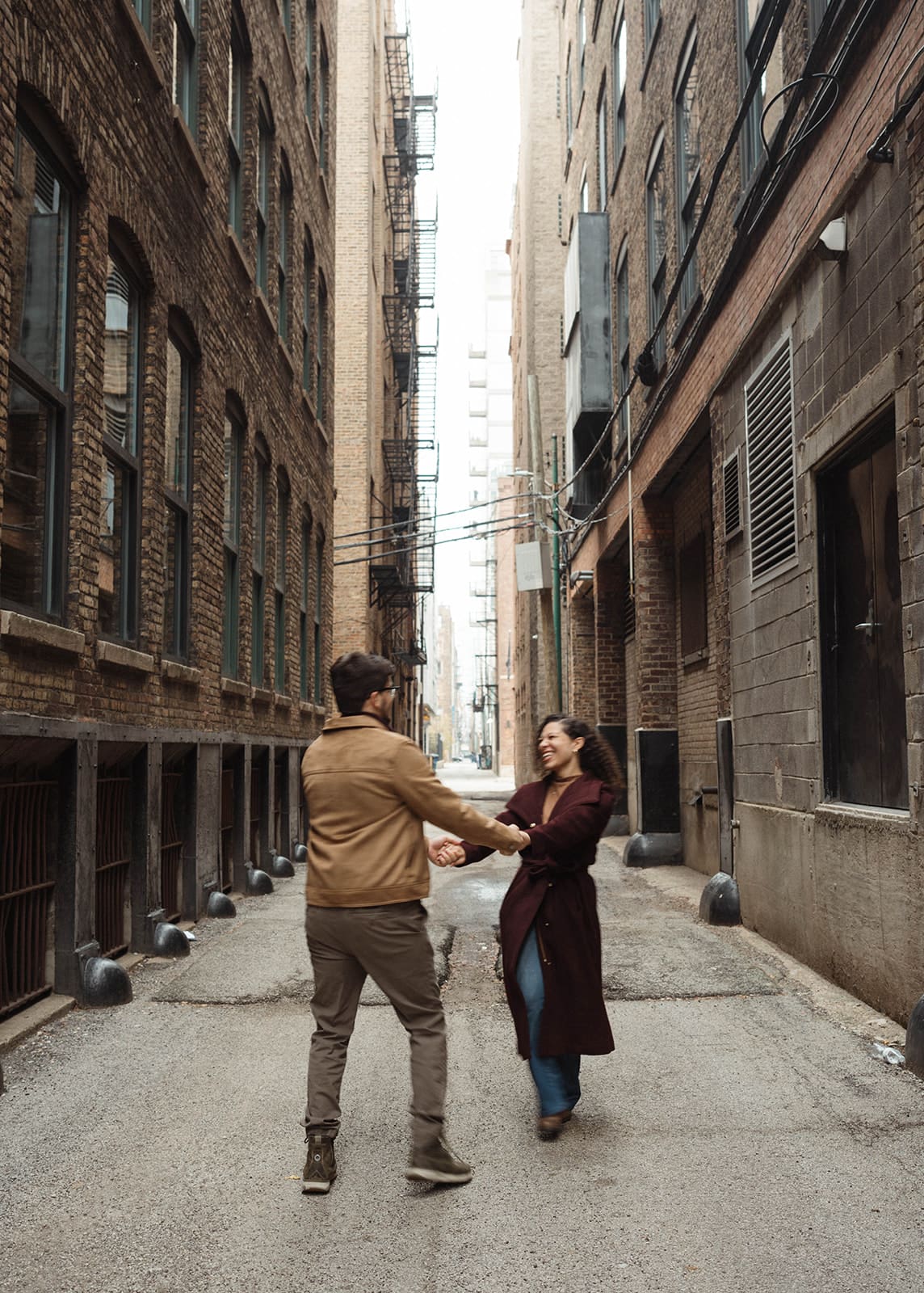 A couple spinning between buildings for their engagement photoshoot