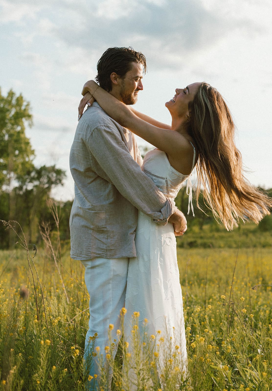A couple posing in a field for their engagement photoshoot