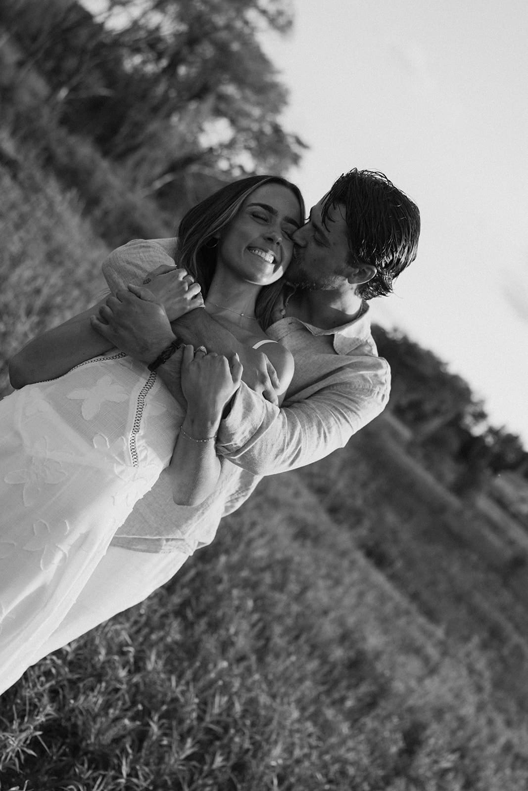 A man kissing his fiancee on the cheek during engagement photos