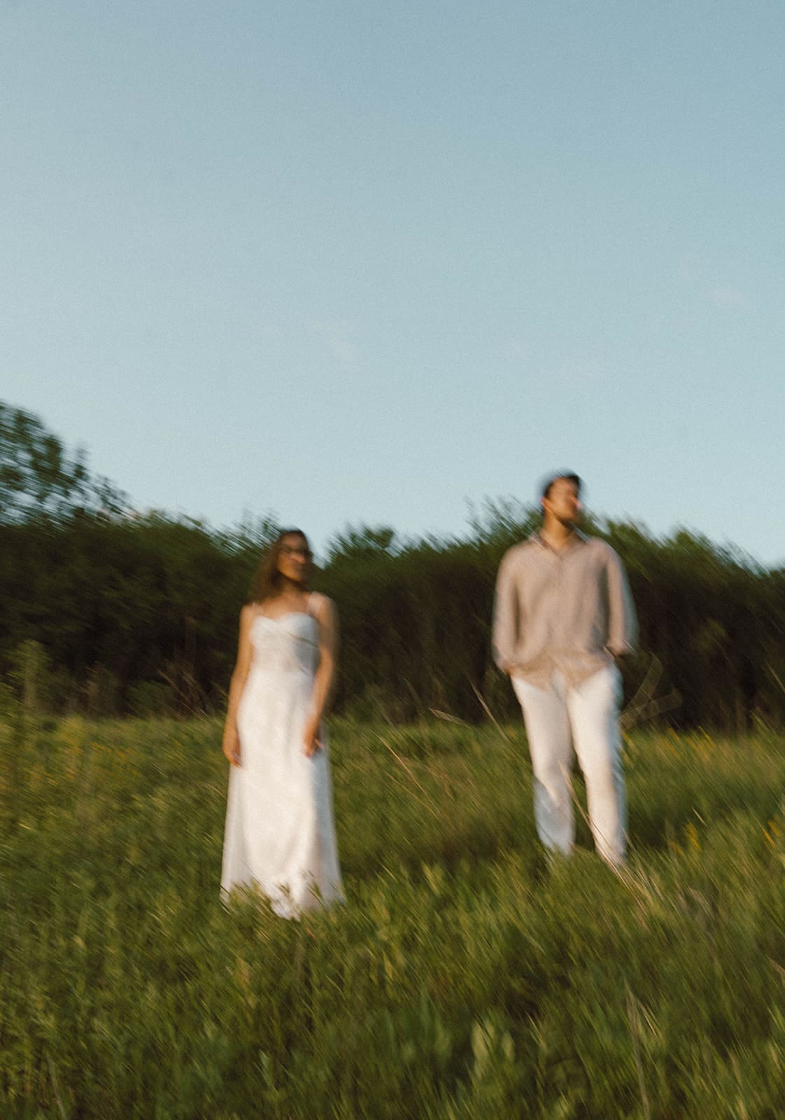 A couple posing for engagement photos in a field