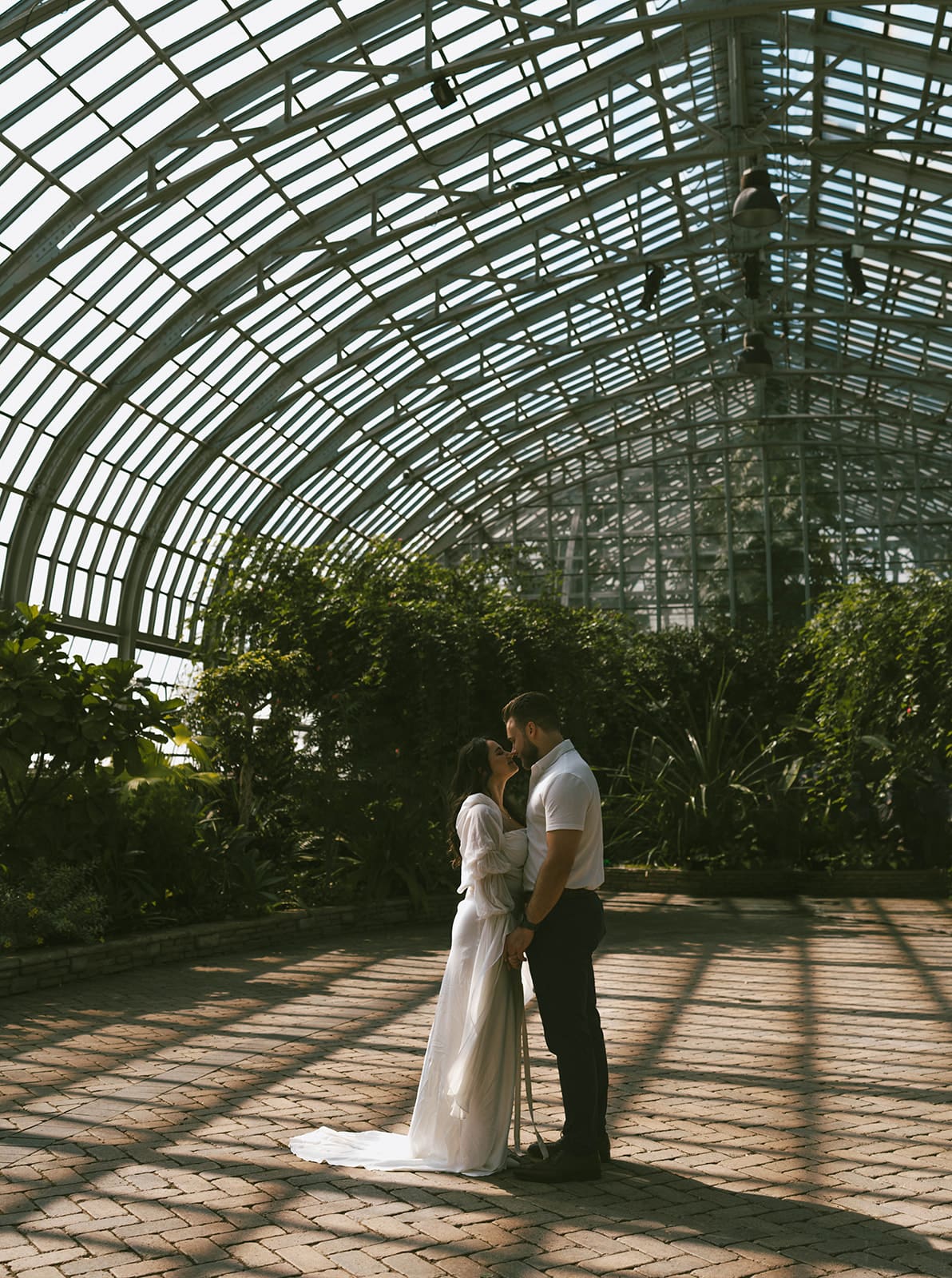 A couple posing for engagement photos in a greenhouse