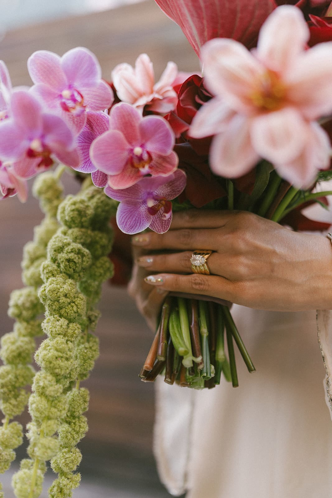A bride holding her pink and red wedding bouquet