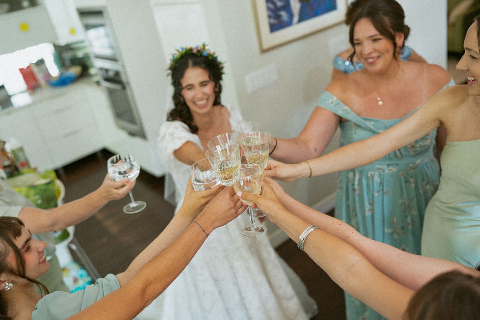 A bride and bridesmaids clinking champagne glasses