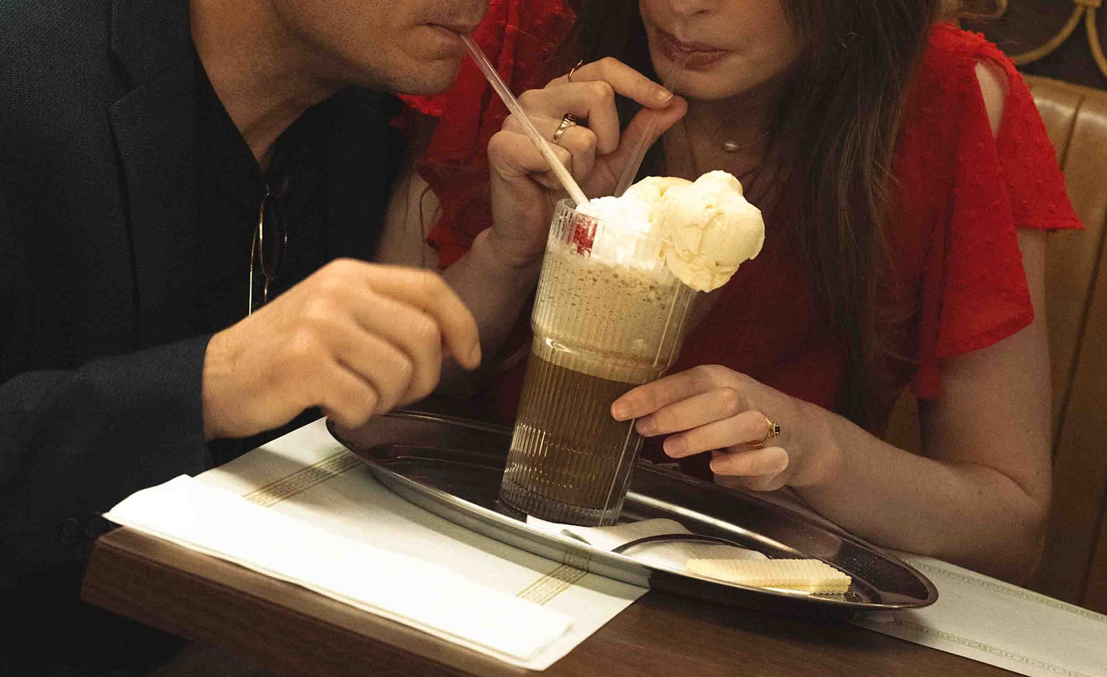 A couple sharing a milkshake during their engagement photoshoot