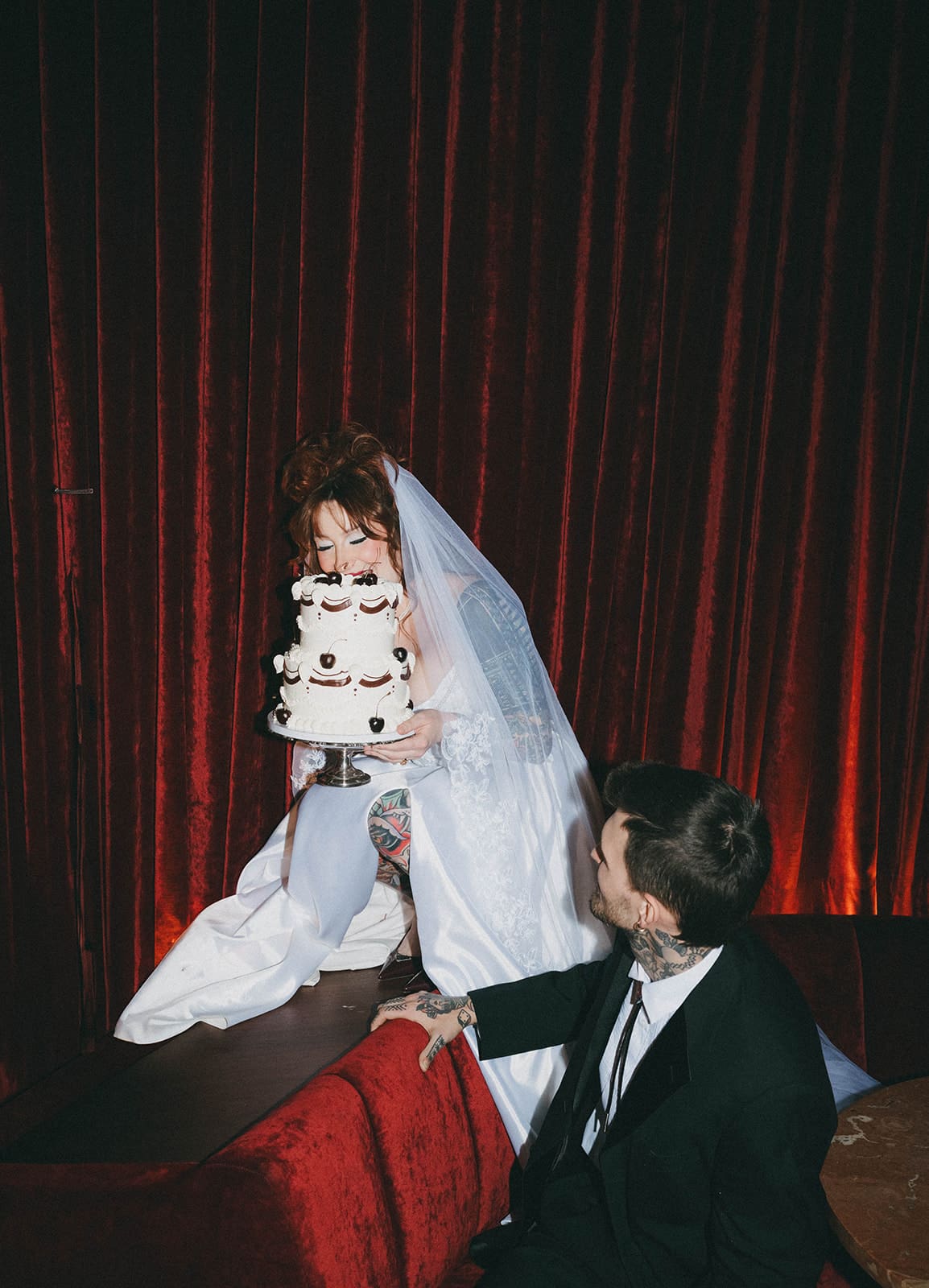 A bride and groom taking photos with their wedding cake