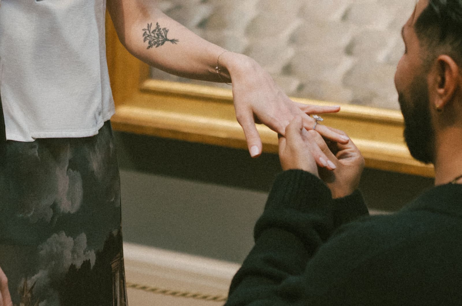 A man putting an engagement ring on his fiancees finger