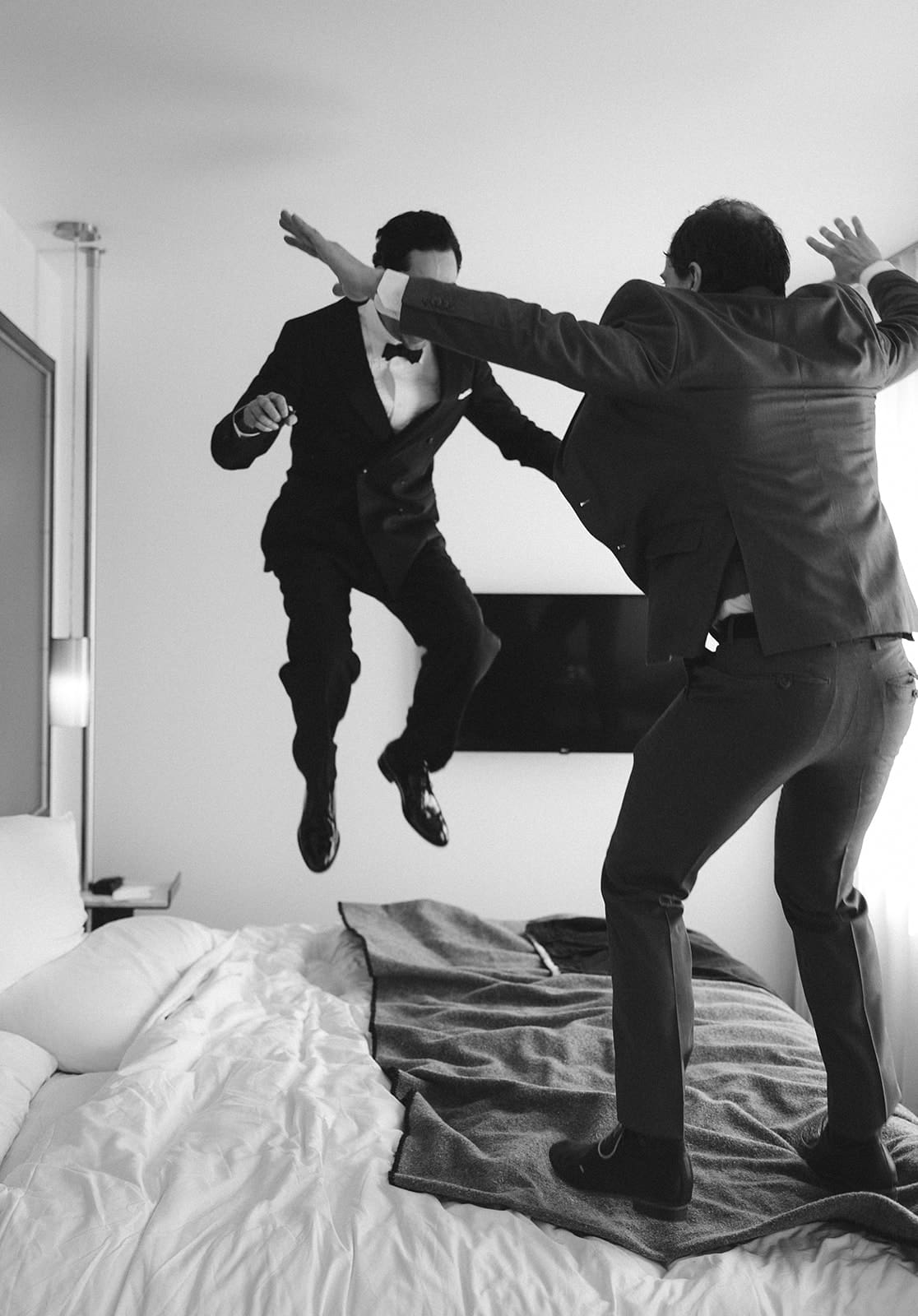 A groom jumping on the bed before his wedding