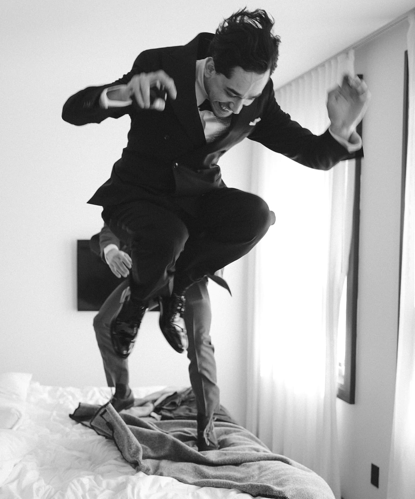 A groom jumping on the bed before his wedding