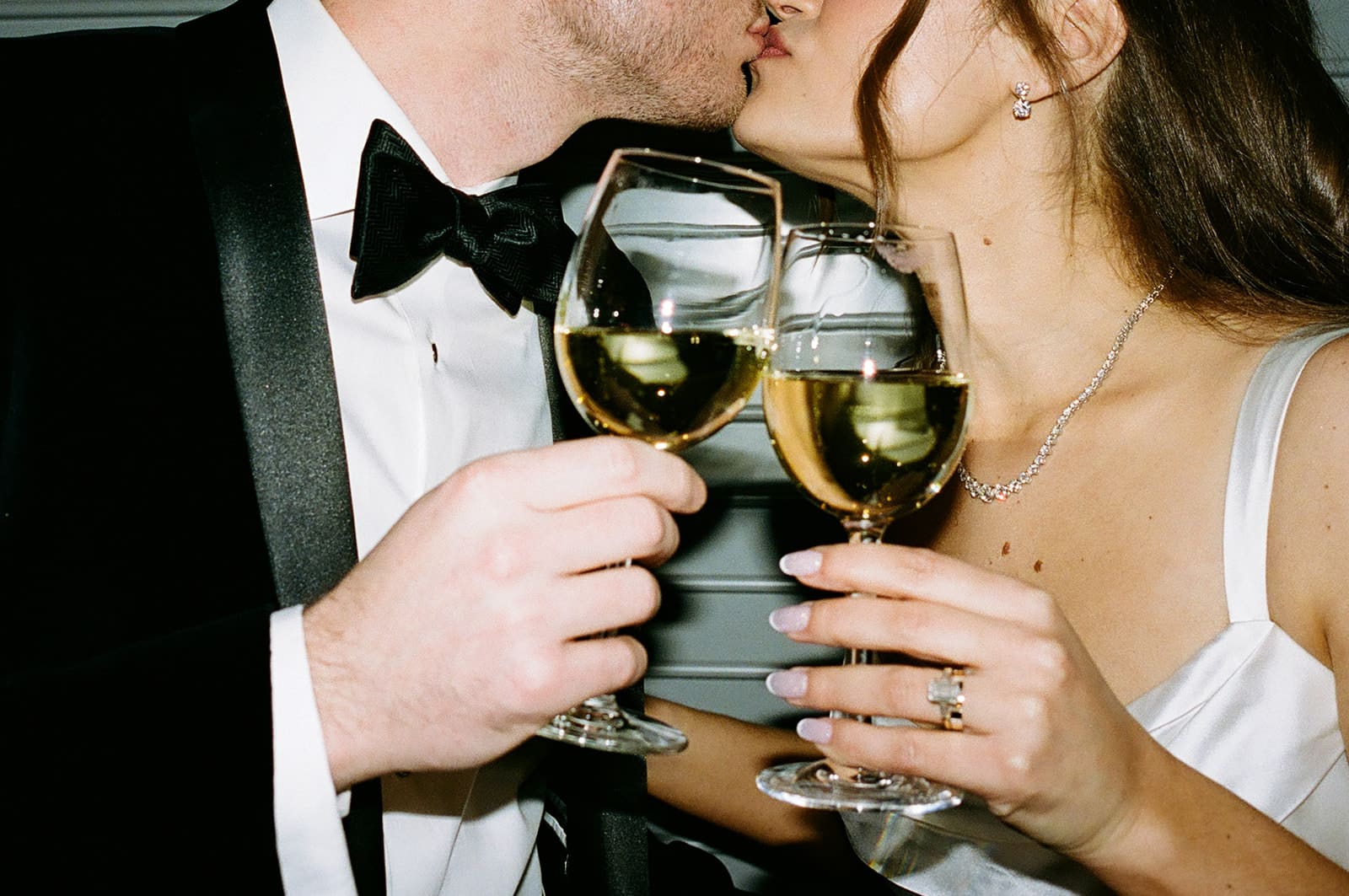 A couple kissing and clinking wine glasses