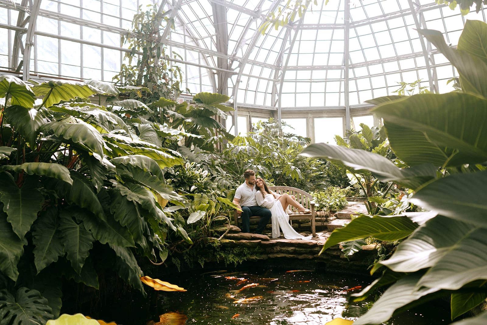 A couple taking engagement photos in a greenhouse during the spring