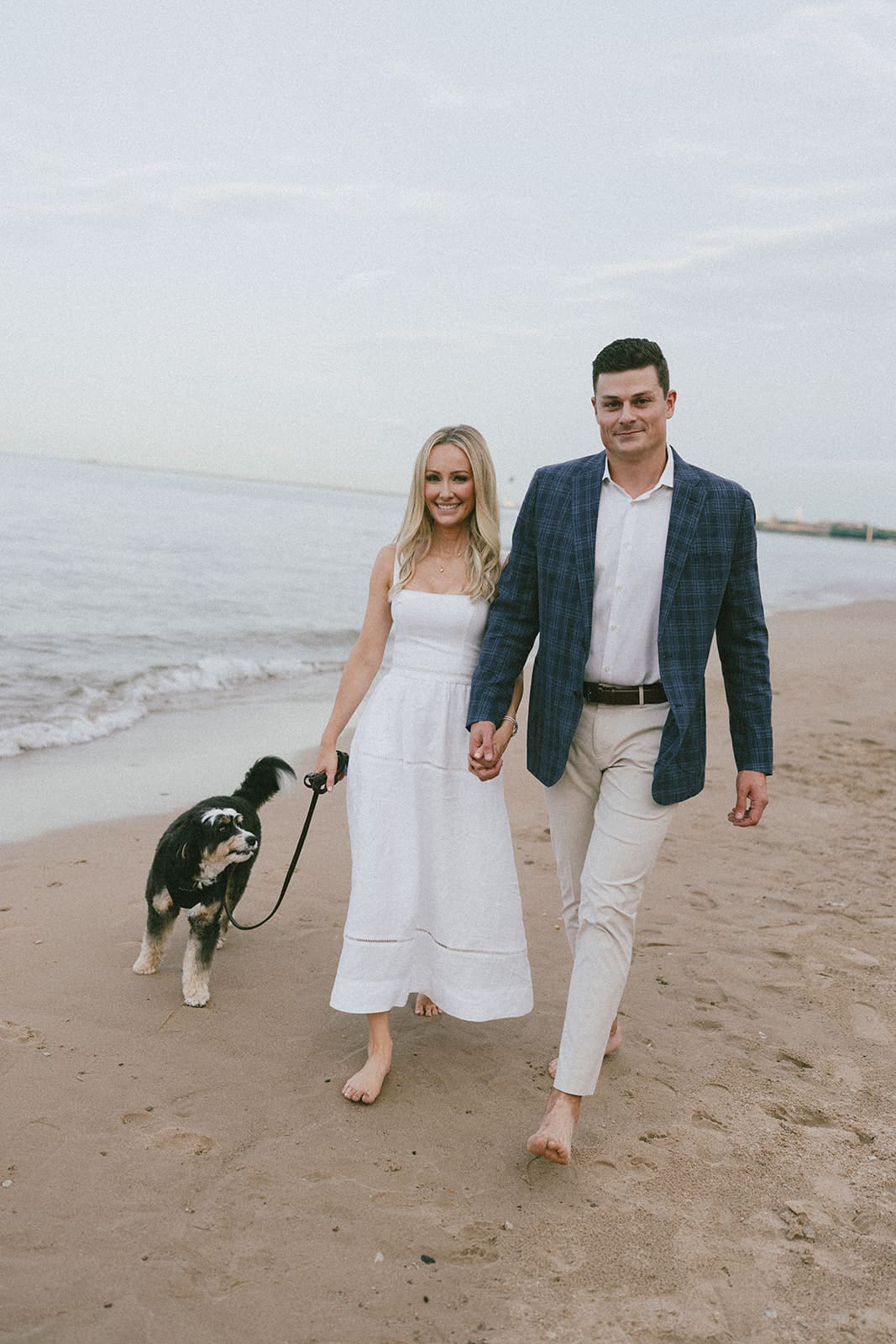 A couple walking on the beach with their dog