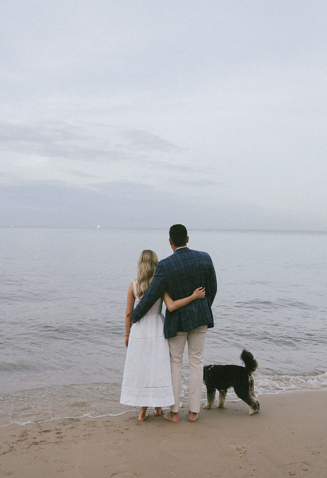 A couple walking on the beach with their dog
