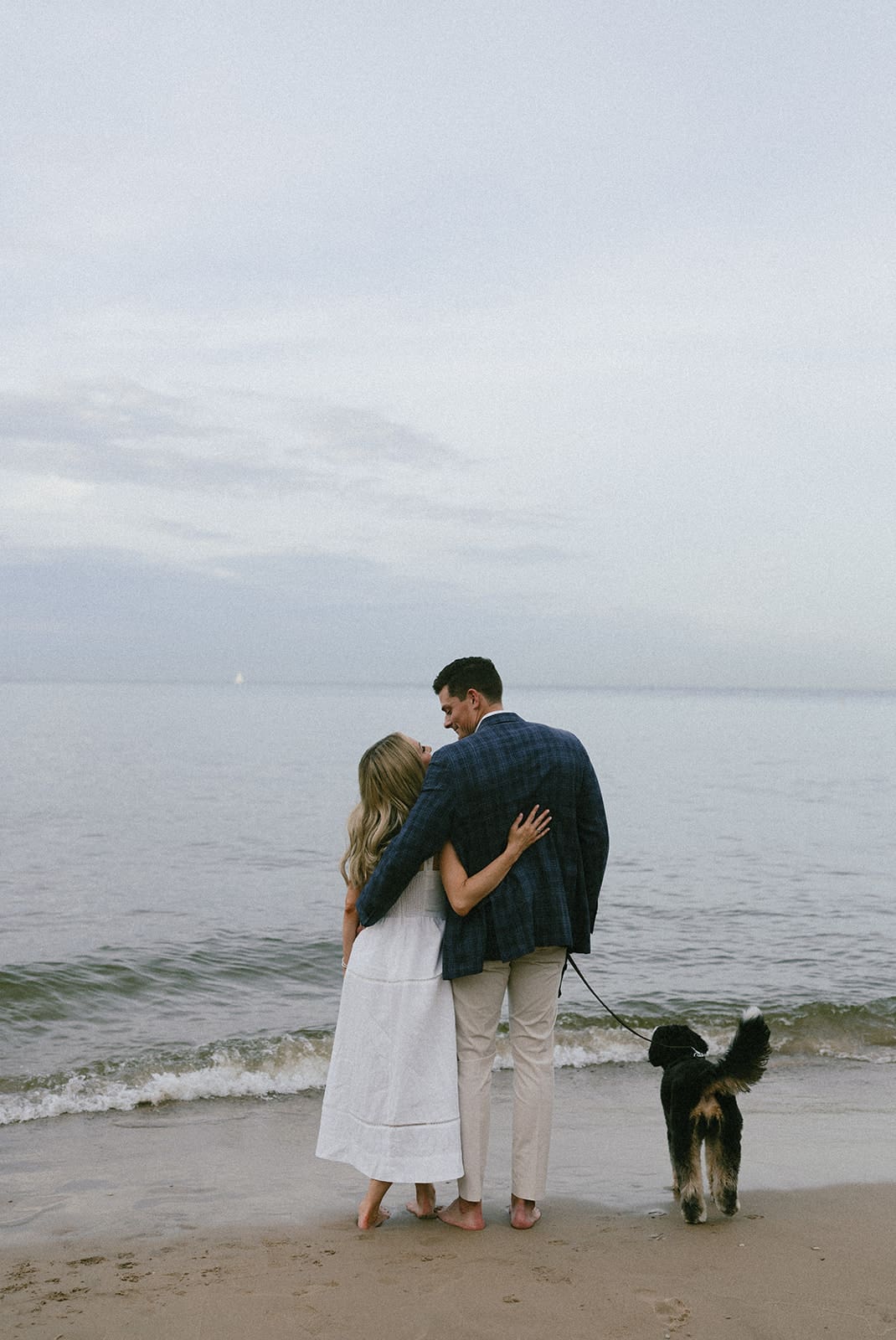 A couple walking on the beach with their dog