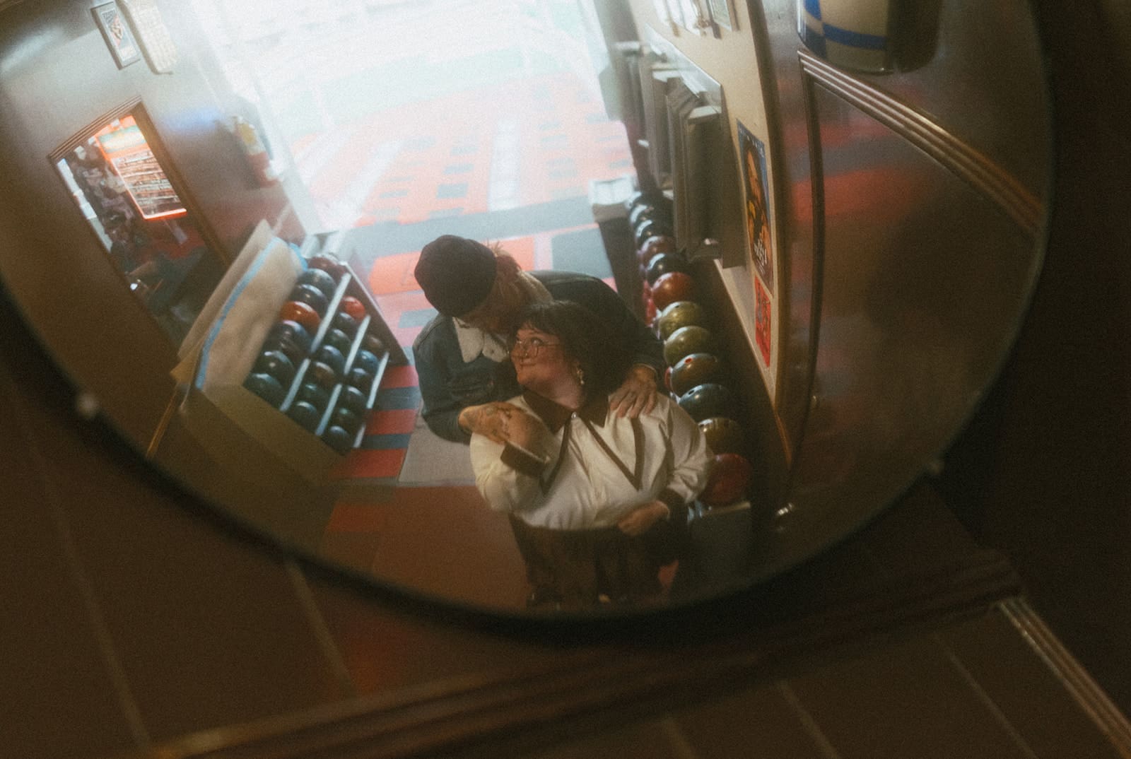 A couple posing for unique engagement photos at a bowling alley