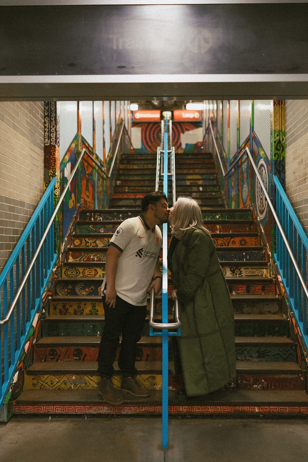 A couple taking engagement photos on painted stairs in Logan Square