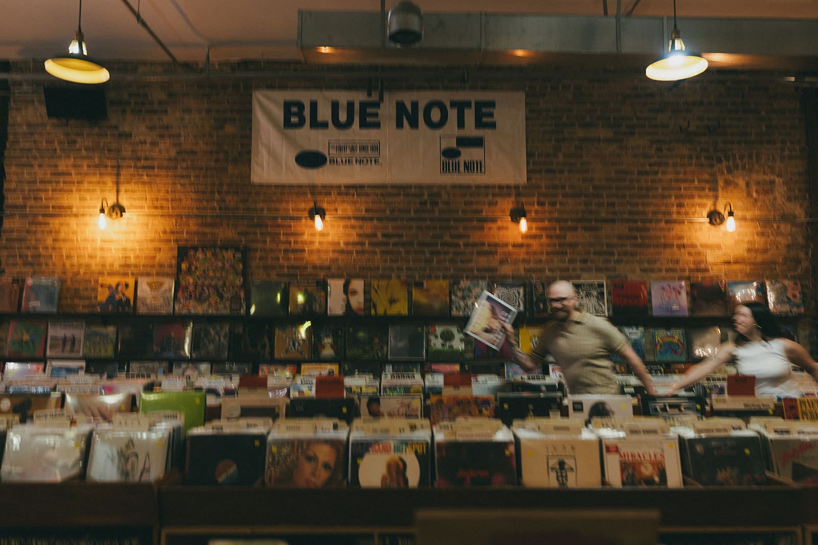 A couple in blurry record store engagement photos